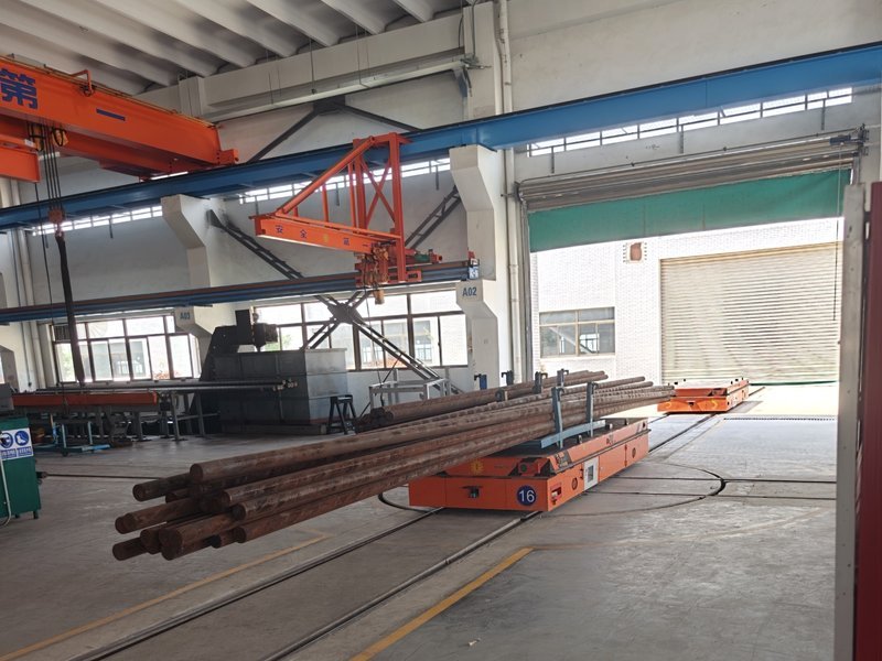 A custom HENSEN rail guided vehicle moving 12-meter machine-tool shafts out of a machining workshop on guided rail track