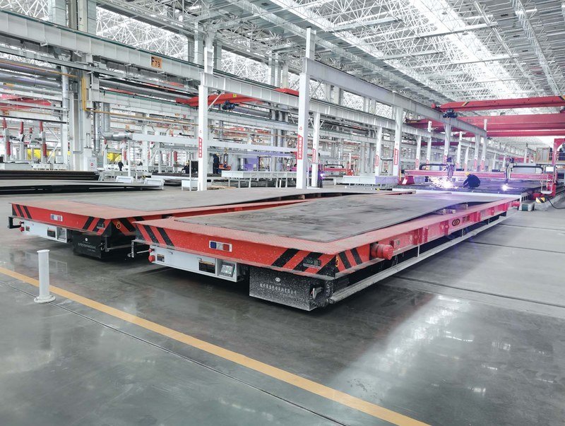 50-ton flatbed RGV rail transfer cart carrying steel plate into warehouse storage