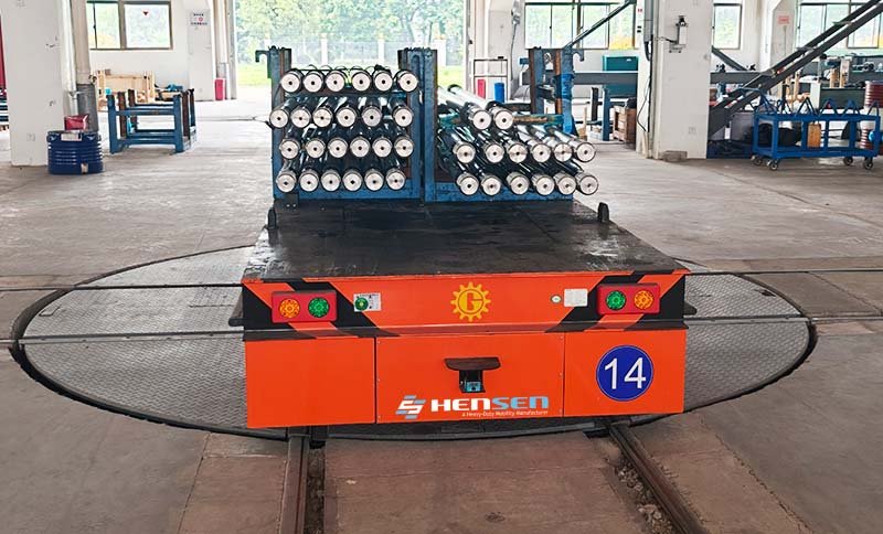 HENSEN Heavy-duty RGV carrying metal bars on a circular rail turntable inside a factory